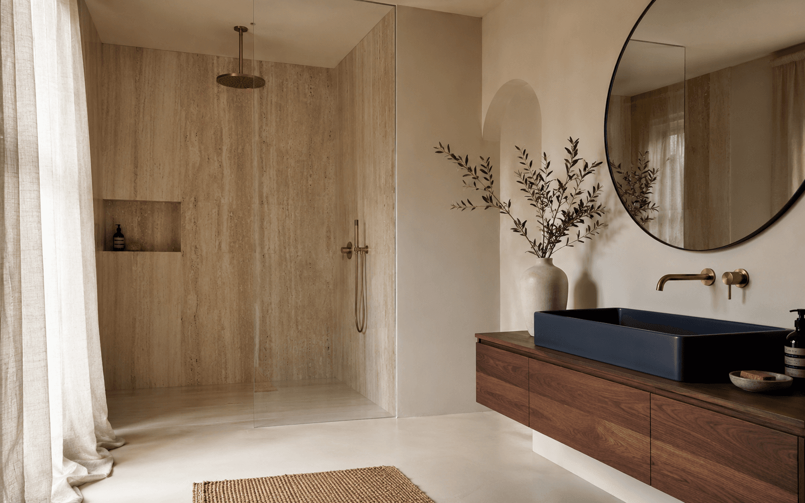 Baño reformado en travertino con ducha walk-in y vanity de madera